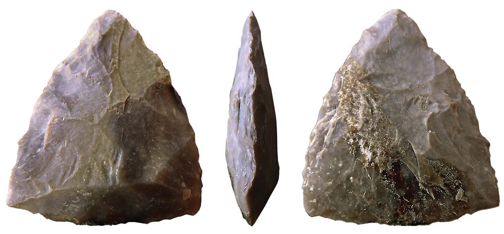 Three views of a prehistoric hand-axe, showing its triangular shape and chipped edges